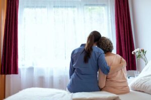 Family member listens to an older adult in a warmly furnished assisted living room.